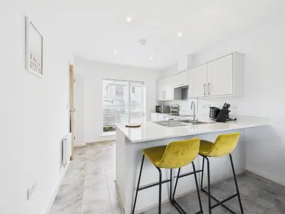 a white kitchen with two yellow chairs at a counter at No4 Harveys Yard By Signature Stays - Luxury Stay - Beach - Parking in Hayle