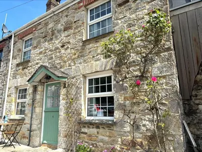 an old stone house with a green door and windows at Holiday Home Rosehip Cottage by Interhome in Pentewan