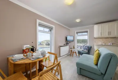 a living room with a table and a blue chair at The Gatehouse Apartment in Portreath