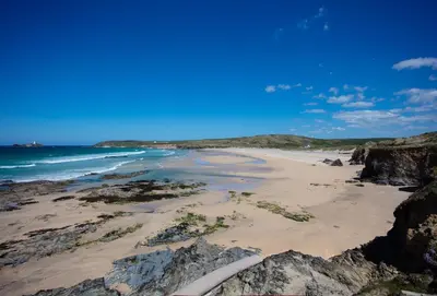 a sandy beach with rocks and the ocean at The Gatehouse Apartment in Portreath