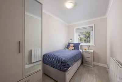 a small bedroom with a bed and a mirror at The Gatehouse Apartment in Portreath