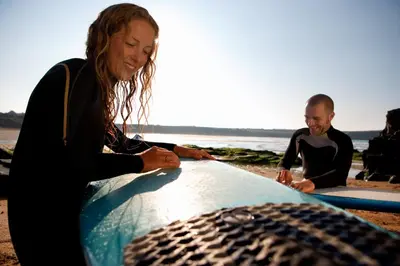two surfers sitting on the beach with their surfboards at Cosy Coastal Falmouth Studio with Free parking & WiFi in Falmouth