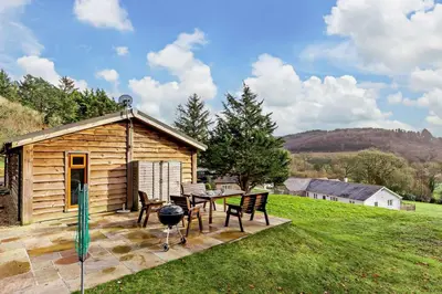 a log cabin with a table and chairs and a grill at 3 Bed in Two Waters Foot oc-m27335 in Cardinham