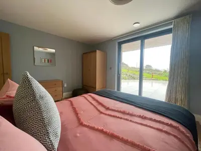a bedroom with a large bed with a large window at Parc an Praze - Cornwall Retreat by the Sea in Perranuthnoe