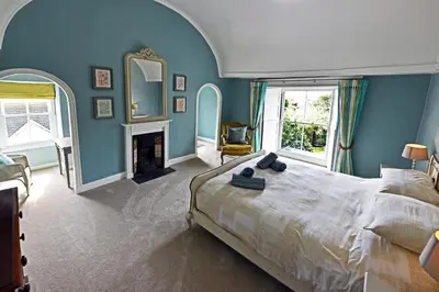 a bedroom with blue walls and a bed and a fireplace at Grade II Listed 17th-Century Rectory in Cornwall in Perranuthnoe