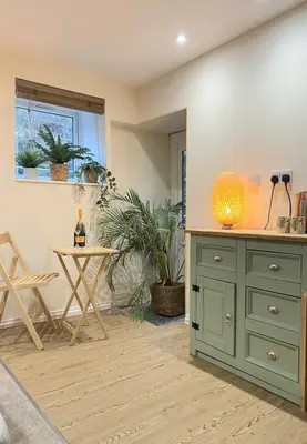 a kitchen with a green cabinet and a table at Cute Cornish Cottage in Saint Germans