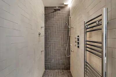 a walk in shower in a bathroom with a tile wall at Finest Retreats - Three Quarter Cottage in Bodinnick