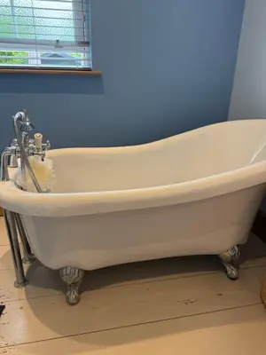 a white bath tub in a bathroom with a blue wall at Buddleia Cottage Trewoon, St Austell in St Austell