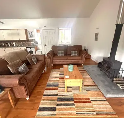 a living room with two couches and a wood stove at Sweetpea - Near Newquay - a tranquil hideaway in Saint Dennis