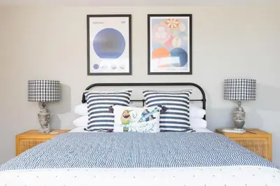 a bedroom with a bed with pillows and two lamps at Tamarind Tide in Portreath