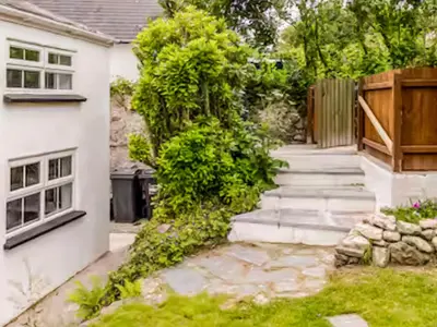 a garden with a walkway next to a house at Sunnyside Cottage Retreat in St Austell
