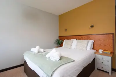 a bedroom with a large bed with towels on it at Tricky's at The Tolgus Inn, Redruth - Free WiFi - Free Parking in Redruth