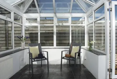 a greenhouse with two chairs in the middle at Little Tresevens in Polzeath