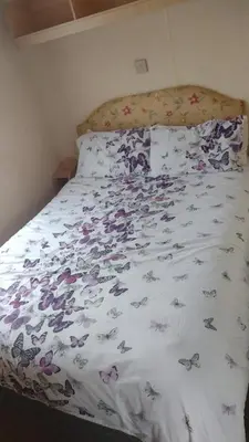 a bed with a white comforter with butterflies on it at Peace Haven in Par