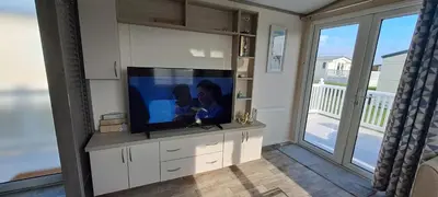 a living room with a flat screen tv on a cabinet at Blue Lagoon Holiday ,Bude 79 in Cubert