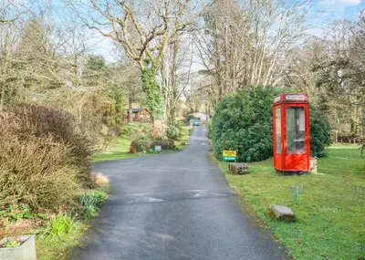 a long road with a red phone booth on the side at Ruthern Valley Holidays in Withiel