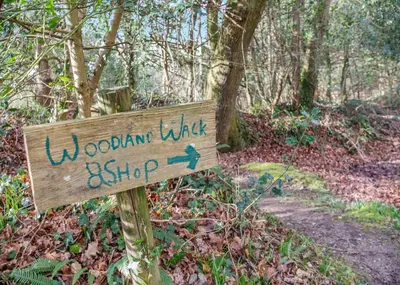 a wooden sign on a trail in the woods at Ruthern Valley Holidays in Withiel