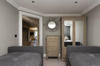 a bedroom with two beds and a dresser and a mirror at Crystal View, Compass Point - Sea View - Free WiFi & Parking - Close to Beach in Carbis Bay