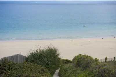 a beach with people on the sand and the ocean at Crystal View, Compass Point - Sea View - Free WiFi & Parking - Close to Beach in Carbis Bay