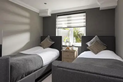 two beds in a room with a couch and a window at Crystal View, Compass Point - Sea View - Free WiFi & Parking - Close to Beach in Carbis Bay