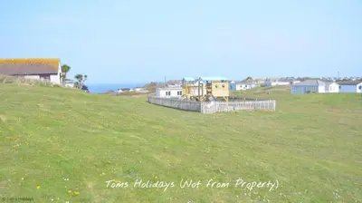 a field of grass with houses on a hill at G24 Trelinda, Riviere Towans in Hayle
