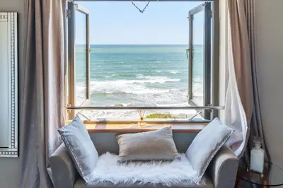 a chair in front of a window with the ocean at Lightkeepers Cottage in Charlestown