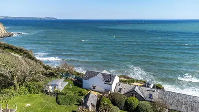a house on a hill next to the ocean at Lightkeepers Cottage in Charlestown