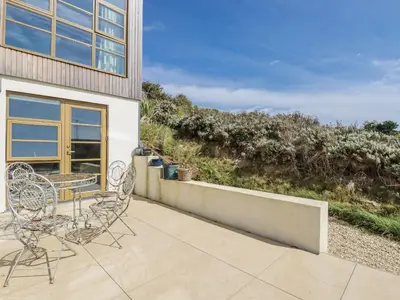 a patio with two chairs and a table on a balcony at Teach Tra East in Perranporth