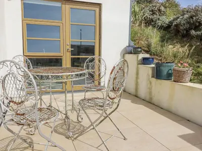 two chairs and a table on a patio at Teach Tra East in Perranporth