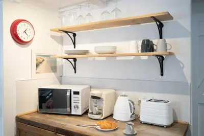 a kitchen with a counter with a microwave and a clock at Klys cottage in Saint Breward
