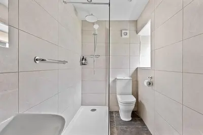 a white bathroom with a toilet and a shower at Fuchsia Cottage in Saint Endellion