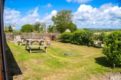 a picnic table in the yard of a stone house at Finest Retreats - Rosemary Cottage in Widemouth Bay