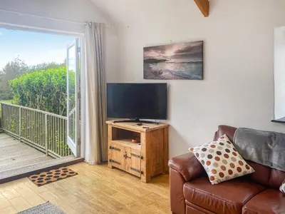 a living room with a couch and a flat screen tv at Swallows in Porthscatho