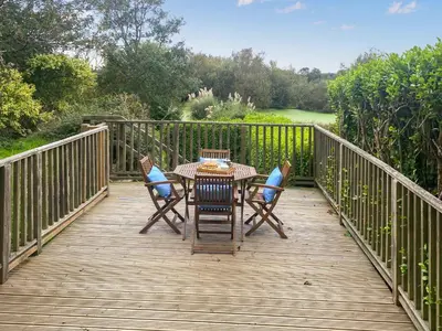a wooden deck with a table and chairs on it at Swallows in Porthscatho