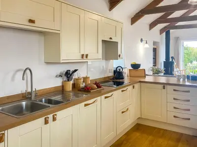 a kitchen with white cabinets and a sink at Swallows in Porthscatho