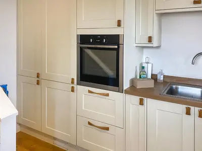 a kitchen with white cabinets and a black oven at Swallows in Porthscatho