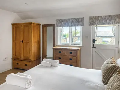 a bedroom with two beds and a dresser and two windows at Swallows in Porthscatho