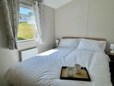 a tray with two cups on a bed with a window at Polperro Seaside Retreat in Polperro