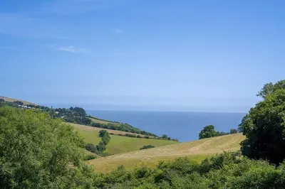 a grassy hill with the ocean in the background at Polperro Seaside Retreat in Polperro