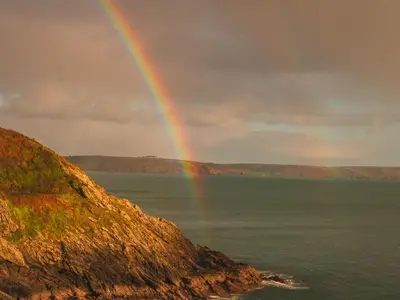 a rainbow in the sky over the water at Holiday Home Shanty Cottage by Interhome in Mevagissey