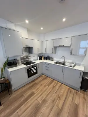 a kitchen with white cabinets and a wooden floor at 1 Bed Apartment in Town Centre in Newquay