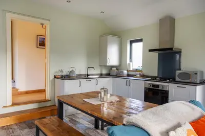 a kitchen with a wooden table and a kitchen with a stove at Middle Barn at Cusgarne Manor, adults only in Cusgarne