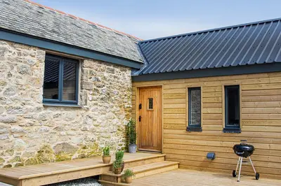 a stone house with a wooden porch and a wooden door at Middle Barn at Cusgarne Manor, adults only in Cusgarne