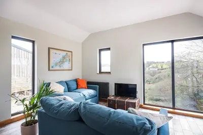 a living room with two blue couches and a fireplace at Middle Barn at Cusgarne Manor, adults only in Cusgarne