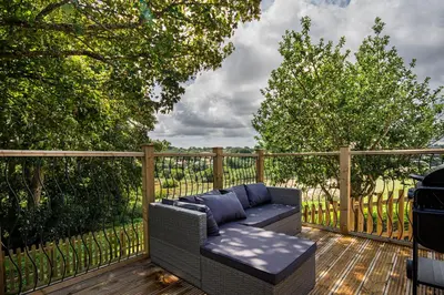 a patio with a couch on a wooden deck at Lowenna at Cusgarne Manor, rural, accessible in Cusgarne