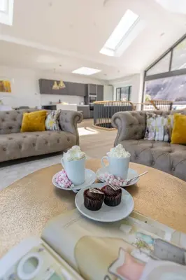 a living room with two cups and cupcakes on a table at Ocean Skies in Porthtowan