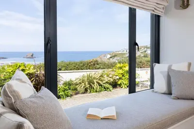 a bed with a book on it with a view of the ocean at Tamarisk in Portreath