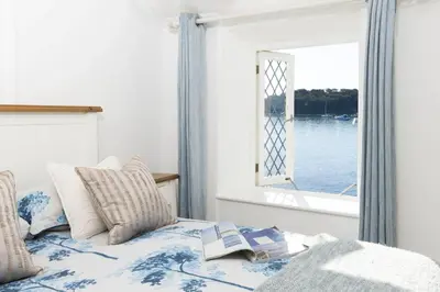 a bed with a book on it with a window at The Old Courthouse in Saint Mawes