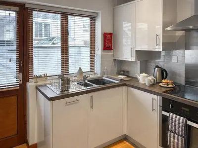 a kitchen with white cabinets and a sink and a window at 4 Porth Cottages in Saint Columb Minor