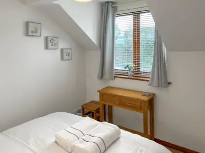 a bedroom with a white bed and a window at 4 Porth Cottages in Saint Columb Minor